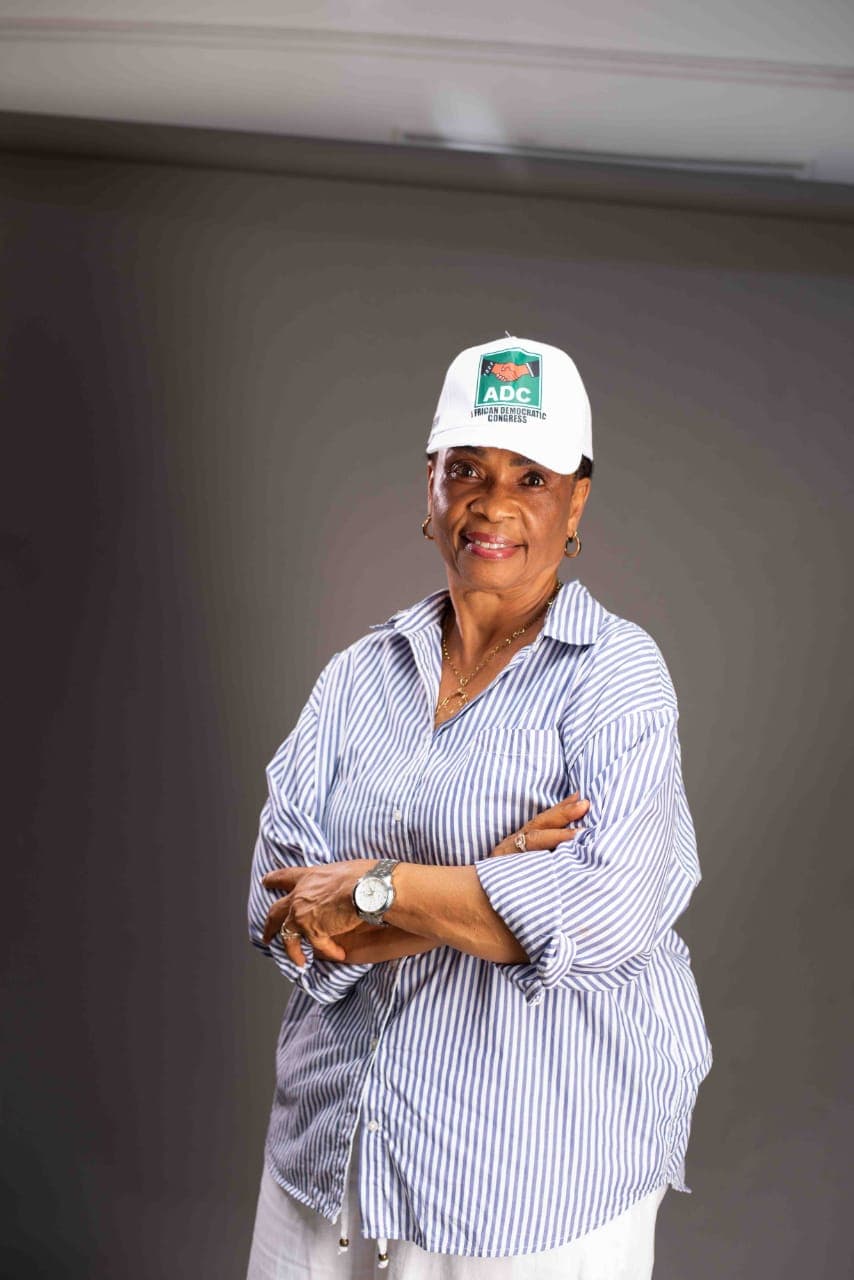 Ambassador Nkoyo Esu Toyo in an ADC cap and striped shirt, arms folded, smiling