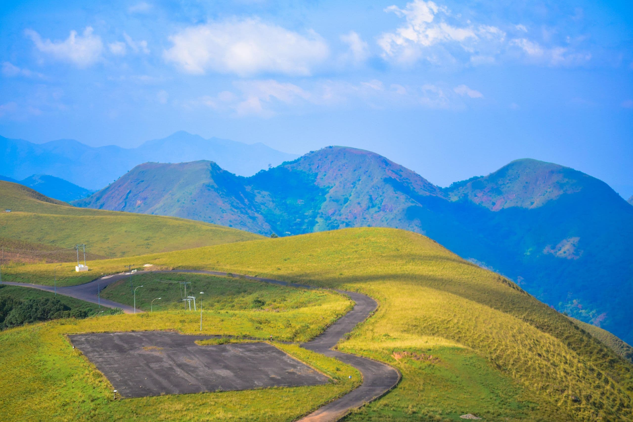A winding road across sunlit hills towards the peaks at Obudu Mountain Resort